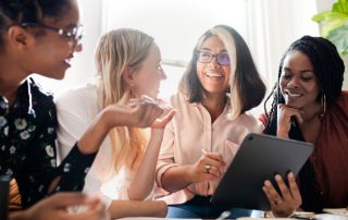 Four women professionals standing at table discussing work