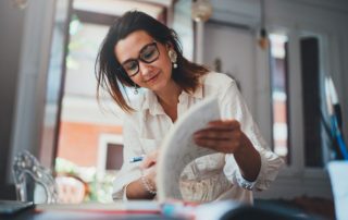 Woman in offfice sitting at desk looking through business paperwork
