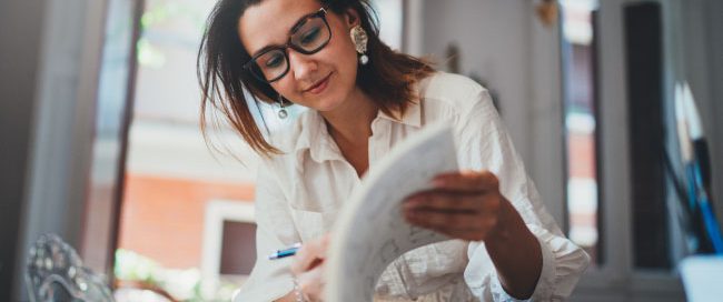 Woman in offfice sitting at desk looking through business paperwork